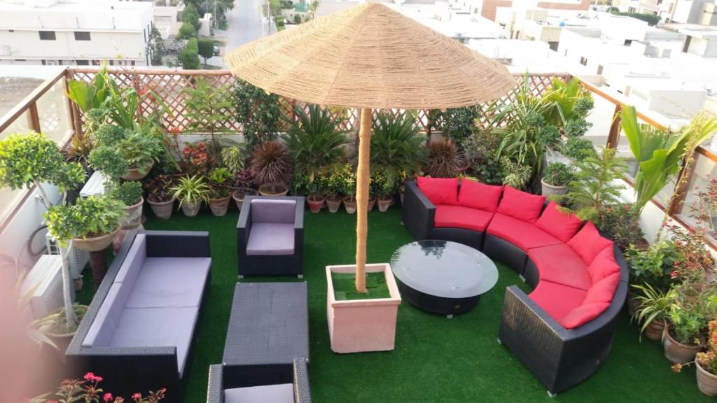 a balcony with chairs and an umbrella and plants at Casa De SAF, Near Sea View, Mc Donalds, Hyper Market in Karachi