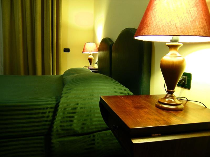 a bedroom with a green bed and a table with a lamp at Relax Style House Central Rooms in Pescara