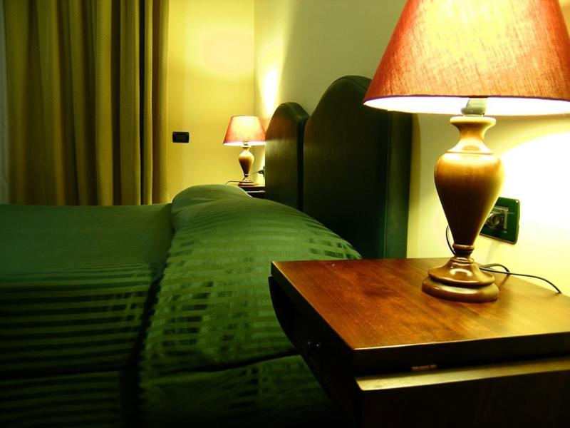 sypialnia z zielonym łóżkiem i stołem z lampką w obiekcie Relax Style House Central Rooms w mieście Pescara