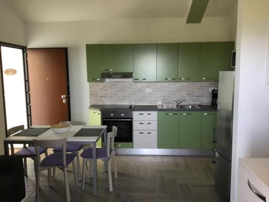 una cocina con armarios verdes, mesa y sillas en Wabi Sabi Resort & Apartments, en Krk