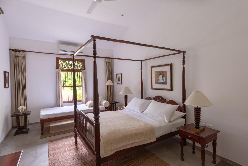 a bedroom with a four poster bed and a window at Nyne Hotels Rock Villa, Bentota in Bentota