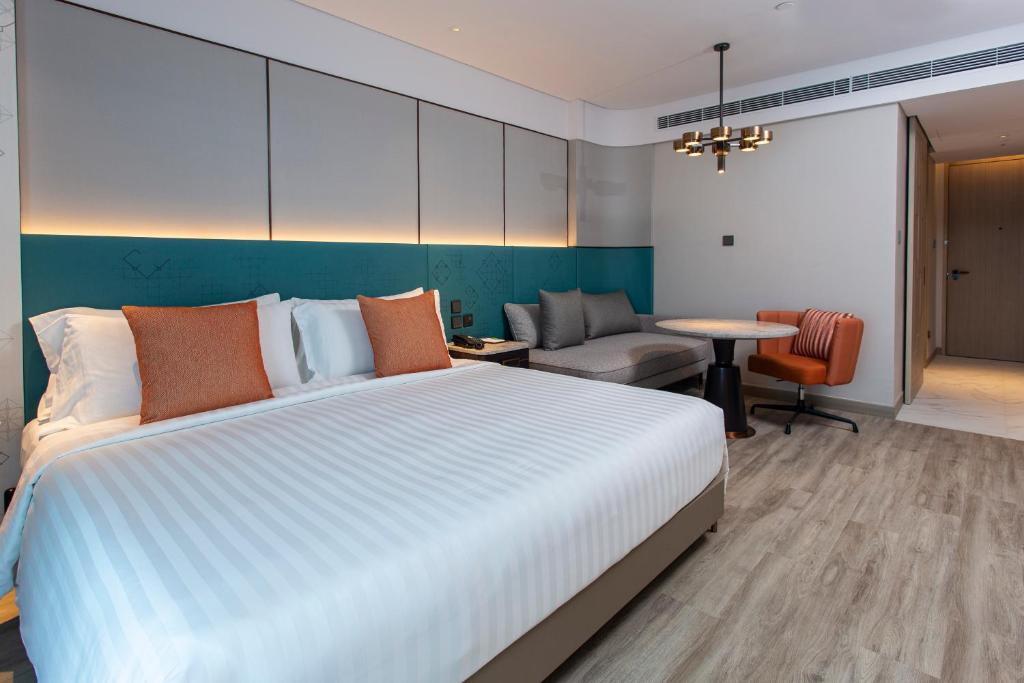 a bedroom with a large bed and a living room at Amari Bangkok in Bangkok