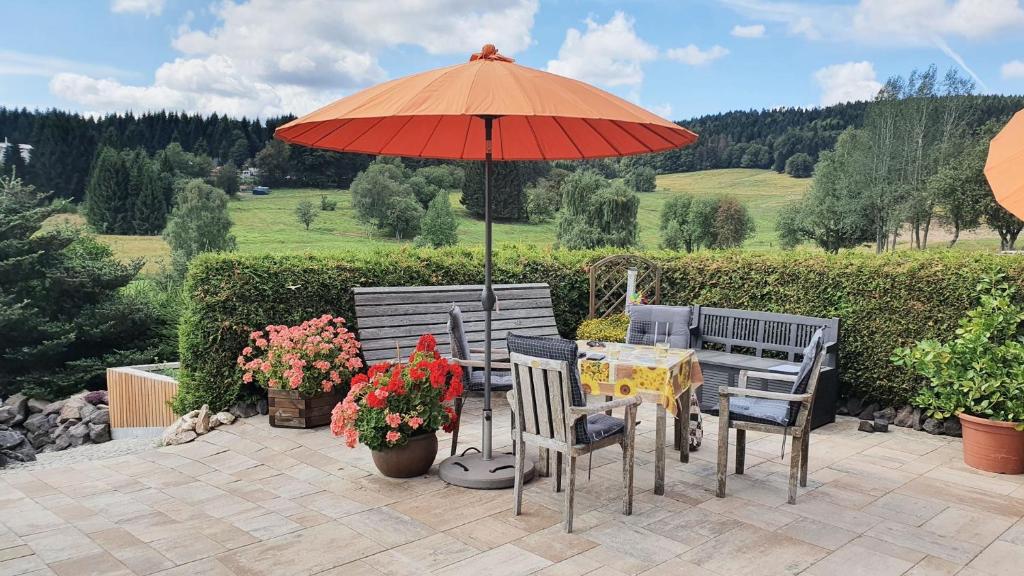 einen Tisch und Stühle unter einem Sonnenschirm auf einer Terrasse in der Unterkunft Monis gemütliche Ferienwohnungen in Schmiedefeld am Rennsteig