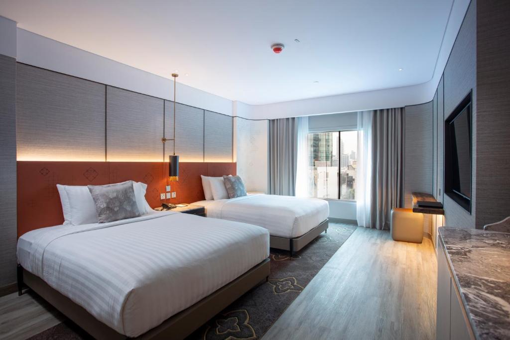 a hotel room with two beds and a television at Amari Bangkok in Bangkok
