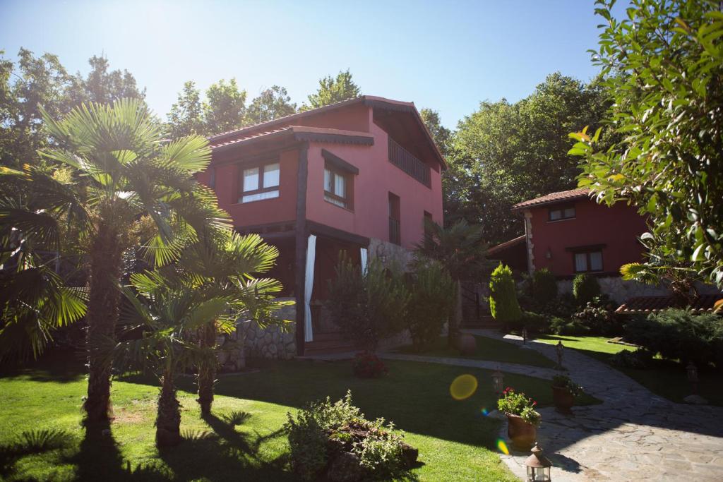 une maison rose avec des palmiers dans une cour dans l'établissement El Rincón de Castilla, à Puerto de Béjar