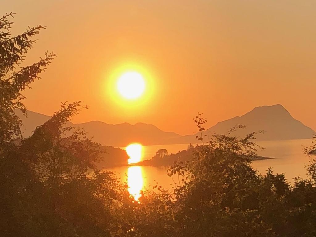 a sunset over a body of water with mountains at Stadlandet - Årsheim stort øko-retro hus tilleie in Stadlandet