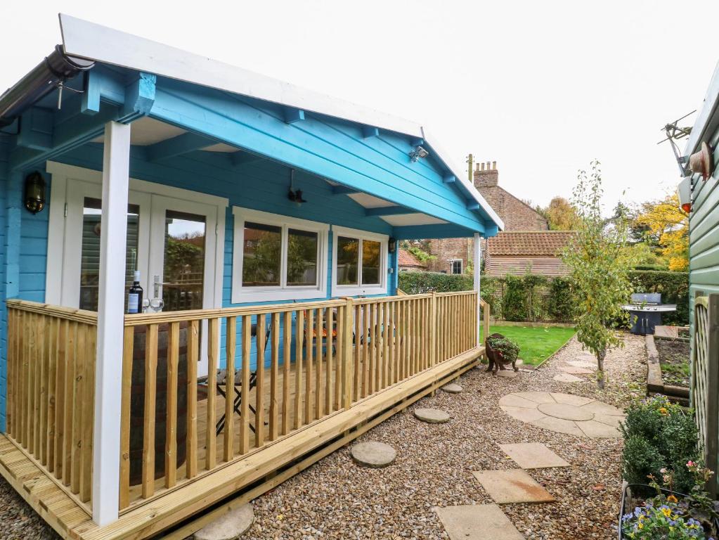 una casa con techo azul y terraza en Beckside Lodge, en Malton