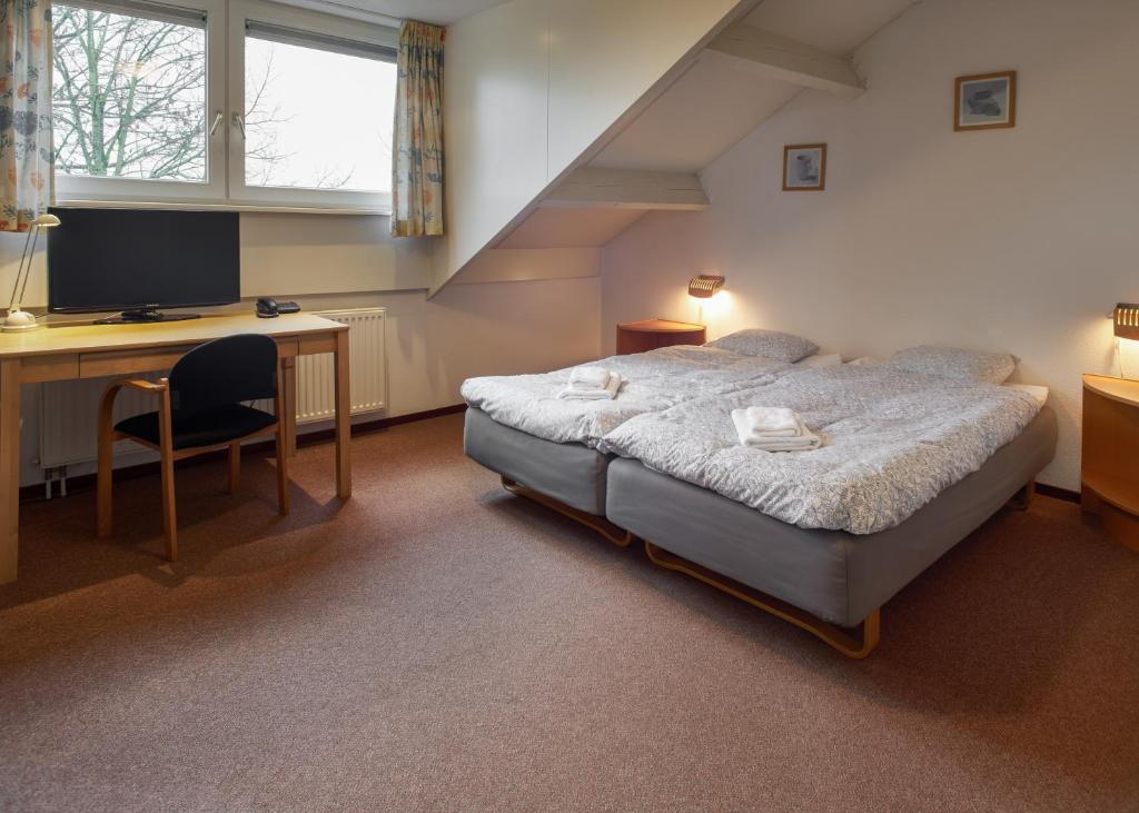 een slaapkamer met een bed, een bureau en een computer bij Vakantiewoningen Ons Krijtland in Epen