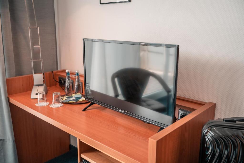 a large flat screen tv sitting on a desk at Airport Lounge Hotel Düsseldorf in Düsseldorf