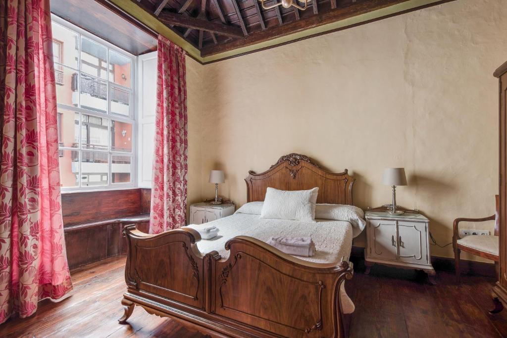 1 dormitorio con cama de madera y ventana en La Vicaría, en La Laguna