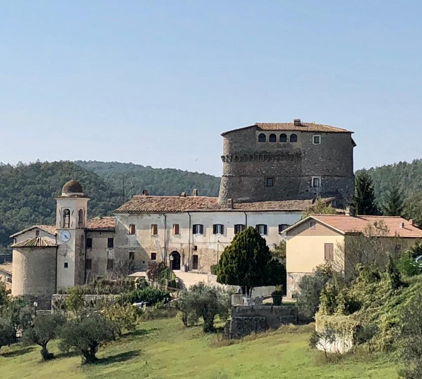 un vecchio edificio con una torre in cima a un campo di Arenarius Home Resort & SPA a Torricella in Sabina