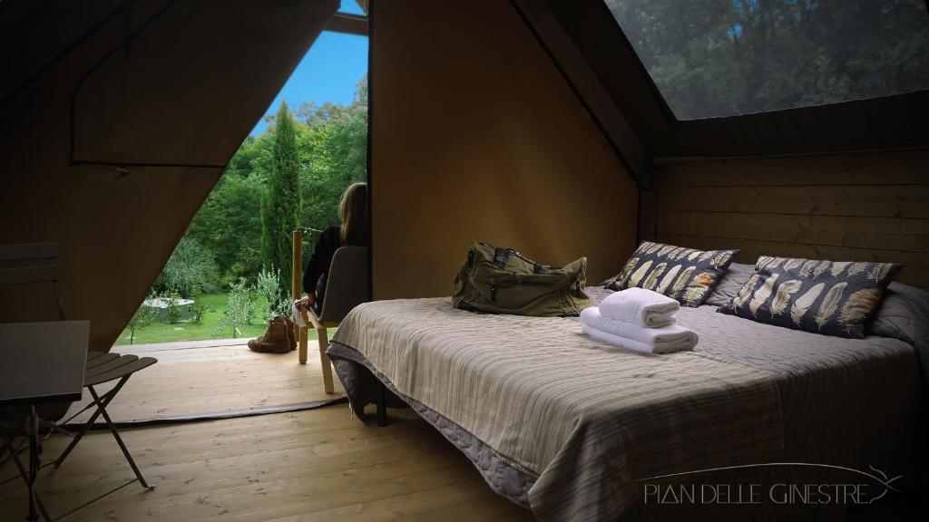 a bedroom with a bed in a room with a large window at Glamping Pian delle Ginestre in Sassetta