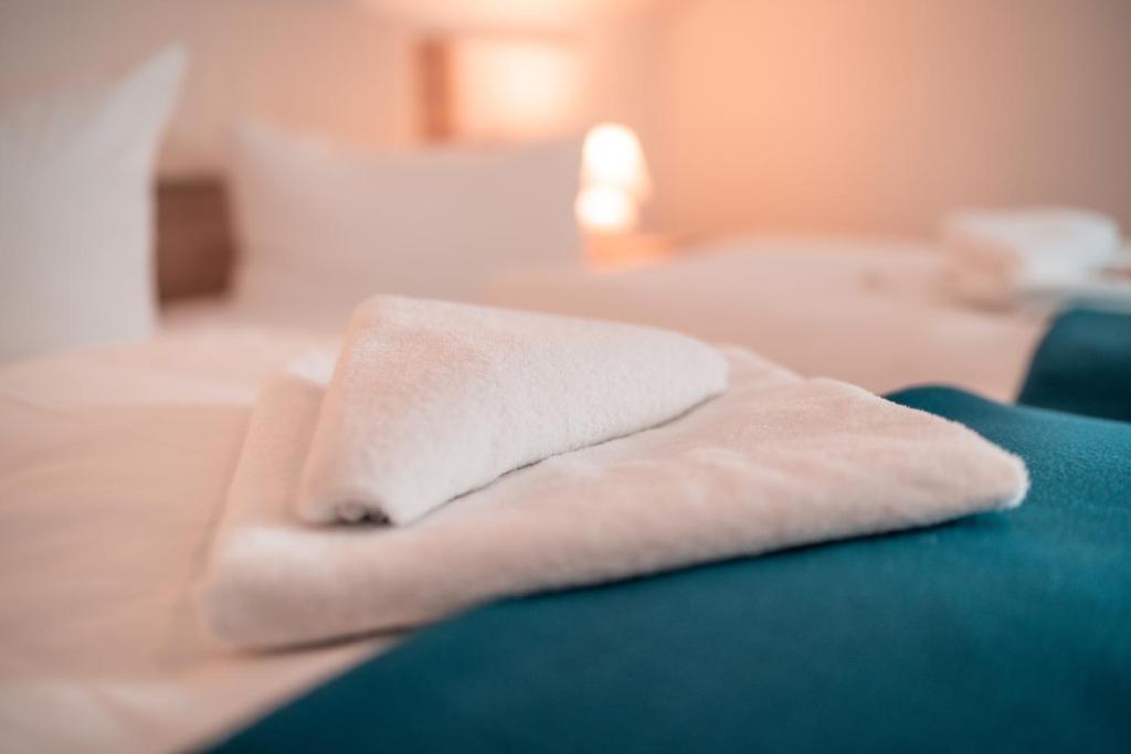 a white towel sitting on top of a bed at Airport Lounge Hotel Düsseldorf in Düsseldorf