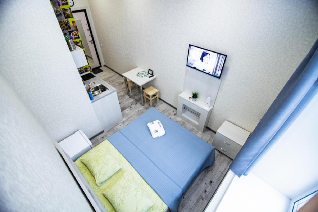 バルナウルにあるСтудия ЦЕНТР города, Красноармейский 96аの青いベッドとテレビが備わる小さな客室です。