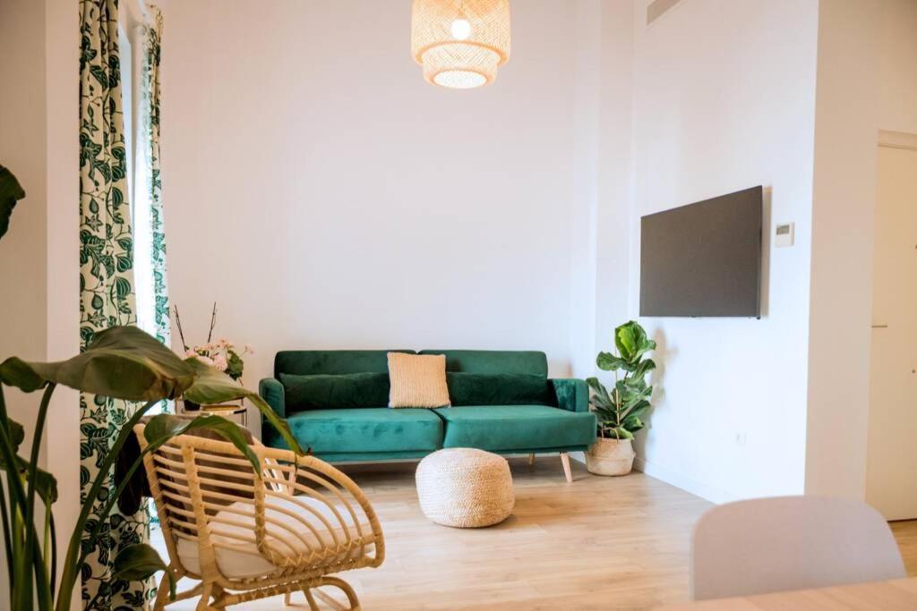 una sala de estar con un sofá verde y plantas en Fantastico apartamento recien renovado con piscina en la azotea, dos dormitorios y aparcamiento gratuito en la calle. en Sevilla