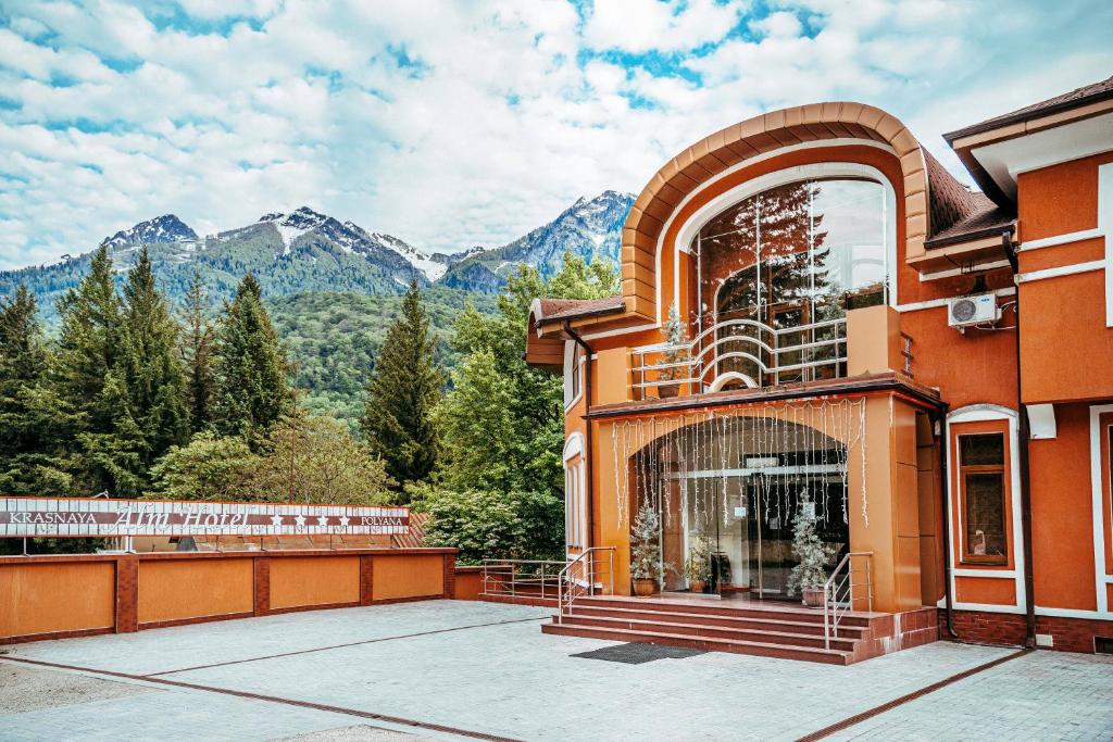 a building with a balcony with mountains in the background at Alm House in Krasnaya Polyana