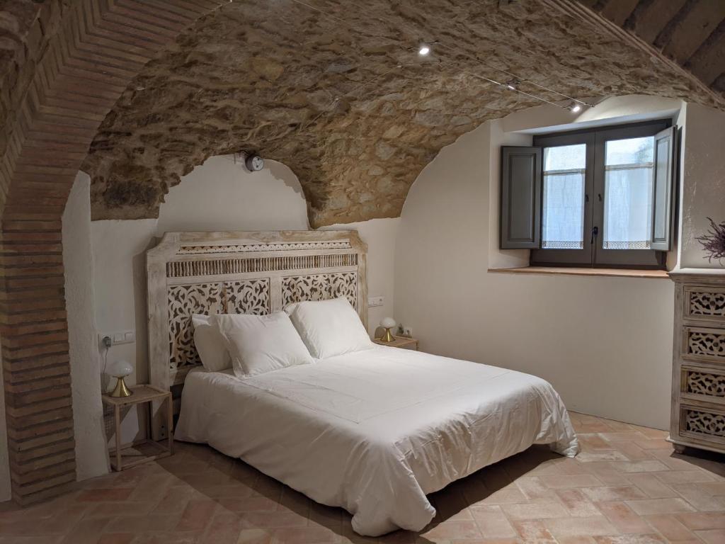 a bedroom with a large white bed with a window at Can Puig CAVE in La Pera