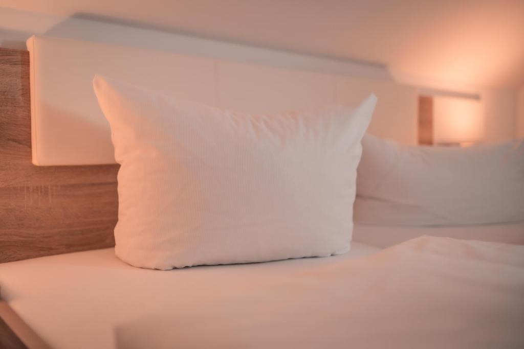 a white pillow sitting on top of a bed at Airport Lounge Hotel Düsseldorf in Düsseldorf