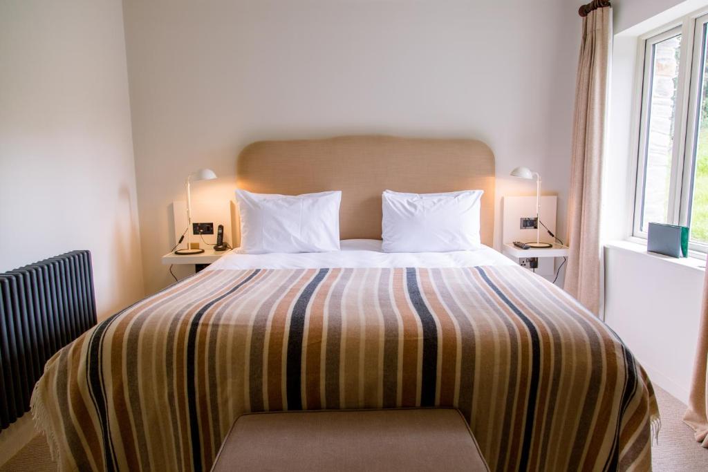 a bedroom with a large bed with a striped blanket at The Plume of Feathers in Mitchell