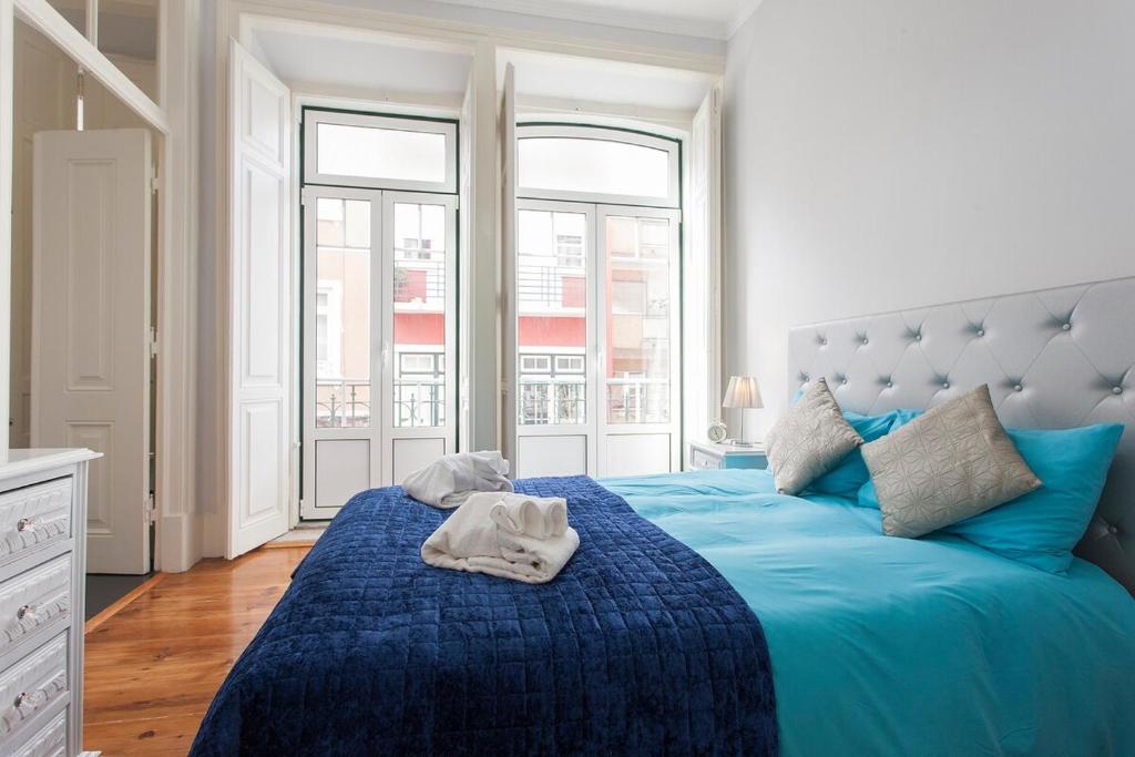 een slaapkamer met een blauw bed en een groot raam bij Traditional & Charm house in Graça in Lissabon