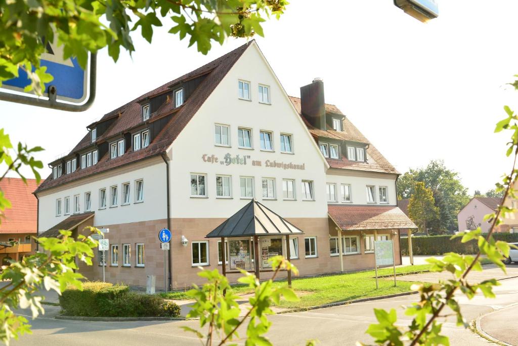 un grand bâtiment blanc avec un toit dans l'établissement Hotel am Ludwigskanal, à Wendelstein