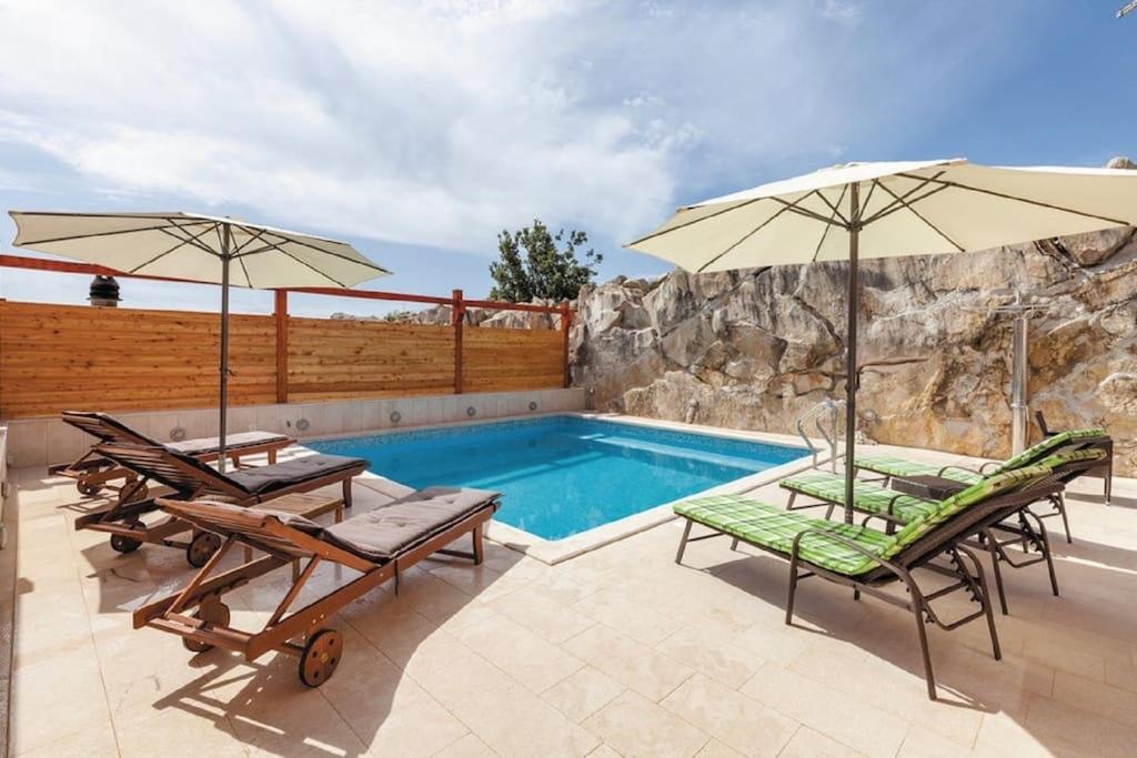 波茲塔納的住宿－Luxury villa Liberta near Split, private pool，一个带两把椅子和两把遮阳伞的游泳池