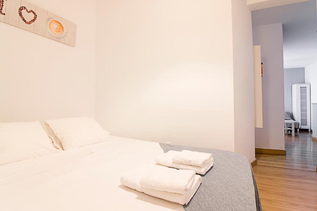 Un dormitorio con una cama blanca con toallas. en Frailes FreshApartments by Bossh! Apartments, en Málaga