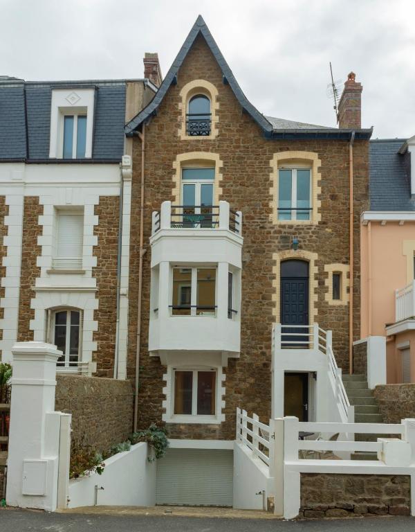 une maison en briques avec une clôture blanche devant elle dans l'établissement La Villa du Sillon, à Saint-Malo