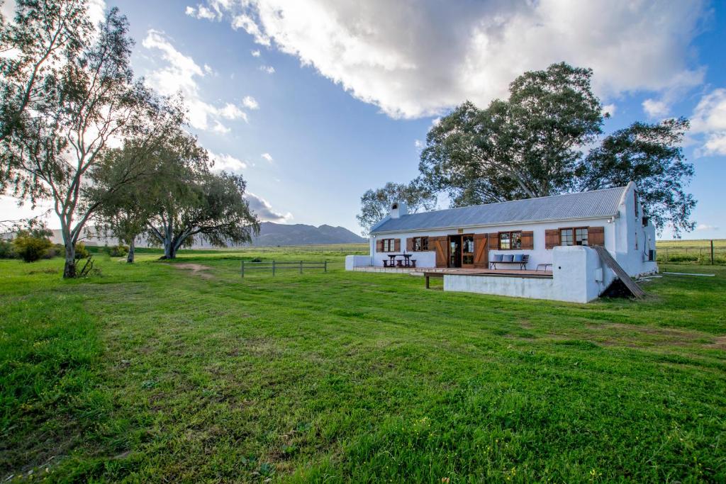 a small white house in a field with a grass yard at Denneboom Vineyards and Wildlife in Paarl