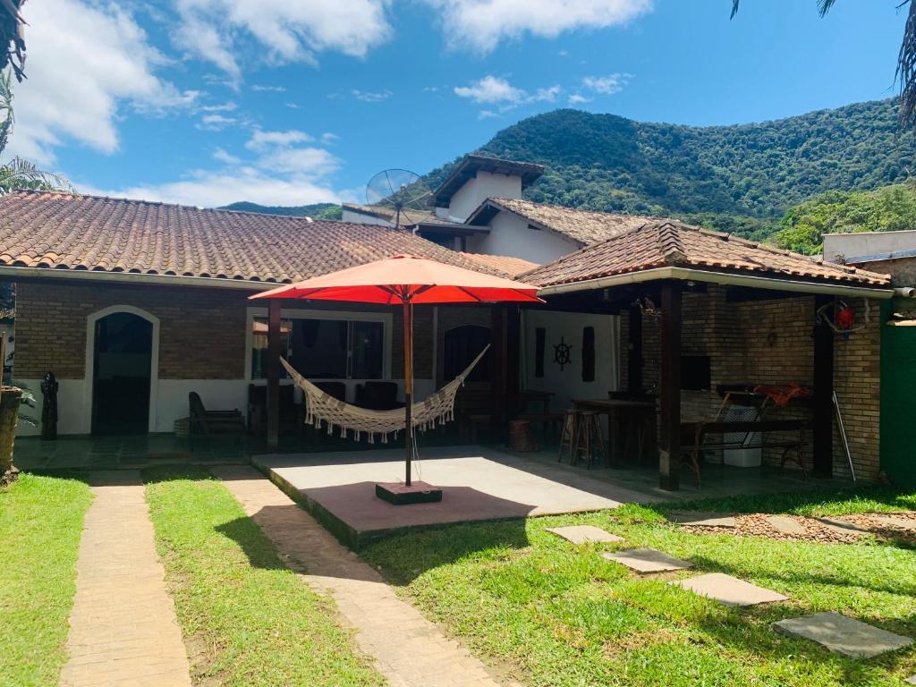 a house with a red umbrella in the yard at Refugio Maresias, para 10 pessoas in Maresias