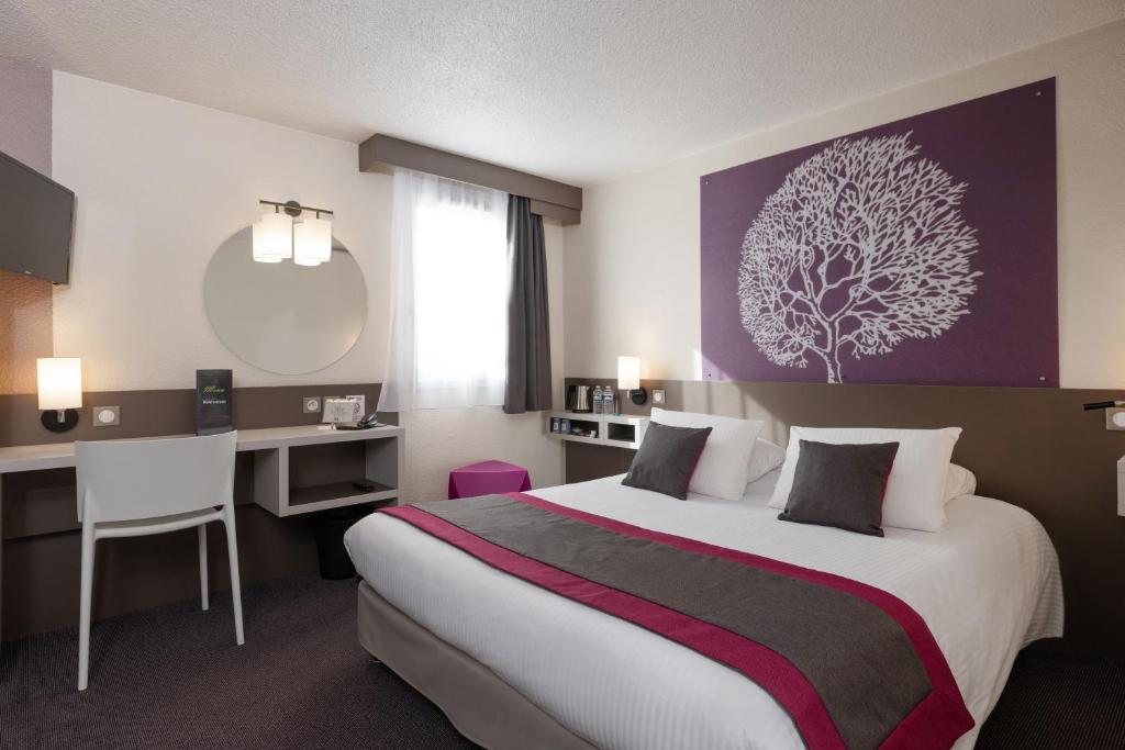 a hotel room with a bed and a desk and a desk at Kyriad Saint-Etienne Centre in Saint-Étienne