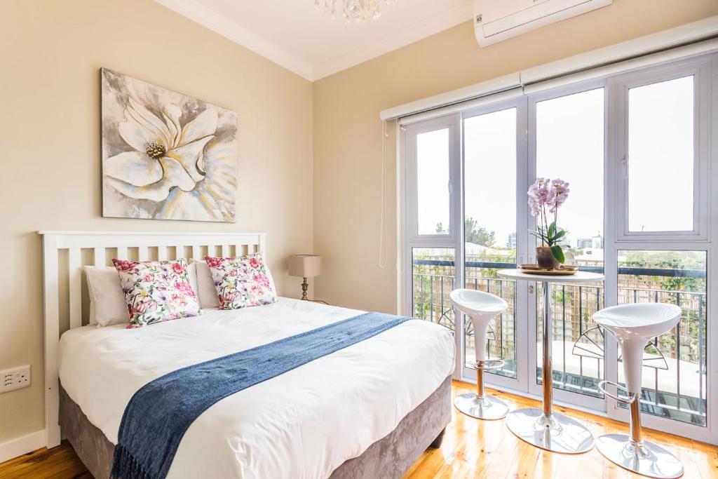 een slaapkamer met een bed en een balkon met ramen bij Vesper Apartments in Kaapstad