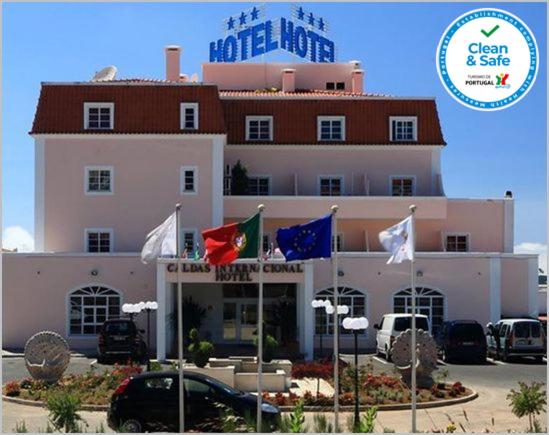 un hôtel avec drapeaux devant un bâtiment dans l'établissement Hotel Caldas Internacional, à Caldas da Rainha