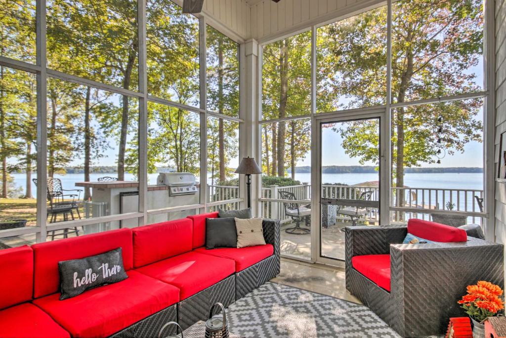a screened in porch with a red couch and chairs at Lakefront Paradise with Fire Pit - Dogs Welcome! in Chappells
