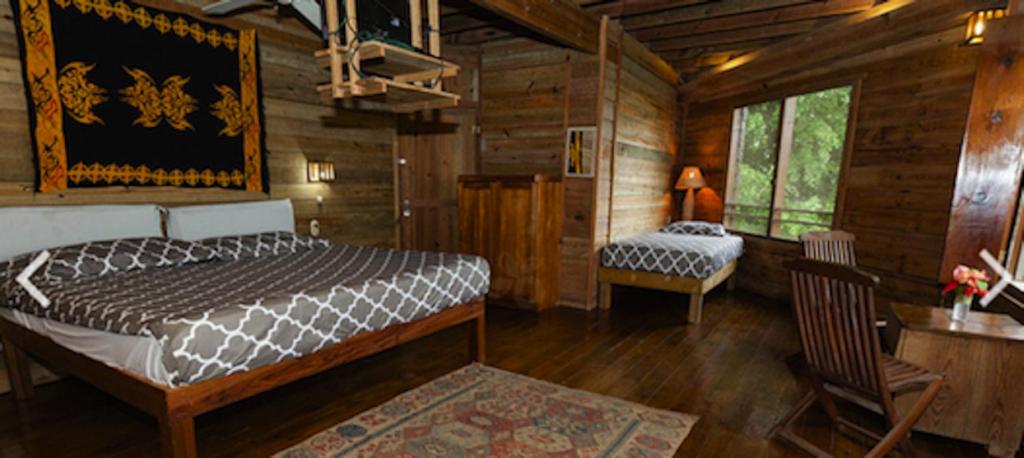 a bedroom with a bed and a chair in a cabin at Roatan Bed & Breakfast Apartments in West End