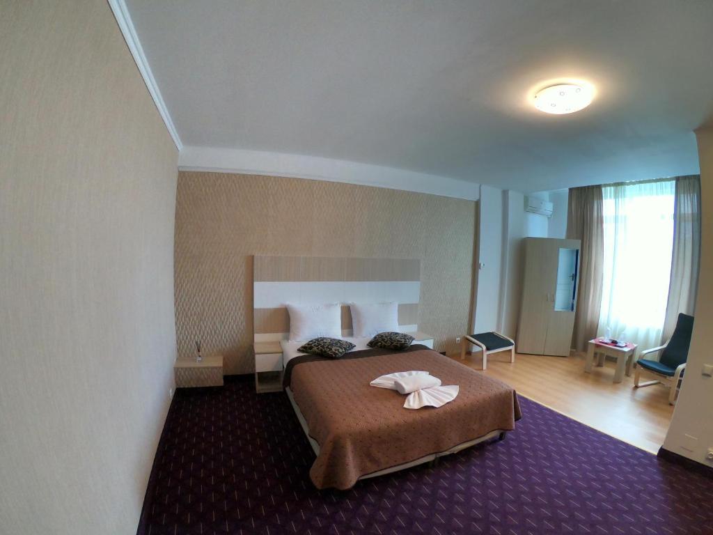 een hotelkamer met een bed met twee handdoeken erop bij Hotel Mon Caprice in Boekarest