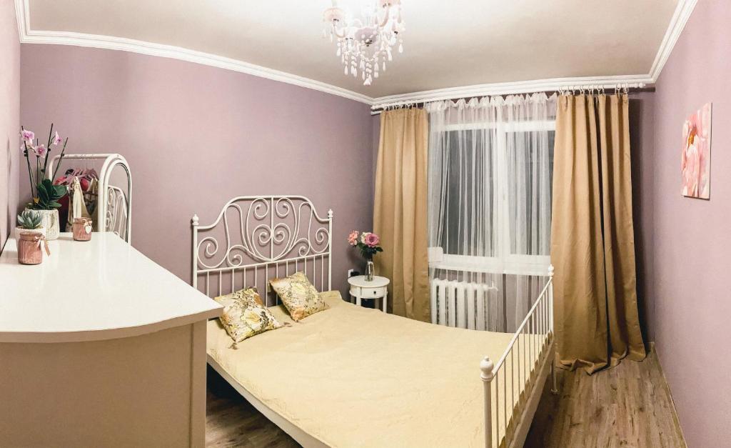 um pequeno quarto com uma cama branca e uma janela em Cosy and Charming apartment em Alūksne