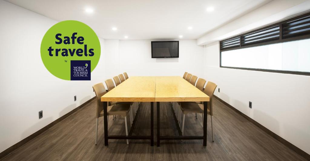 A simple private meeting room with a long table and wall-mounted screen.