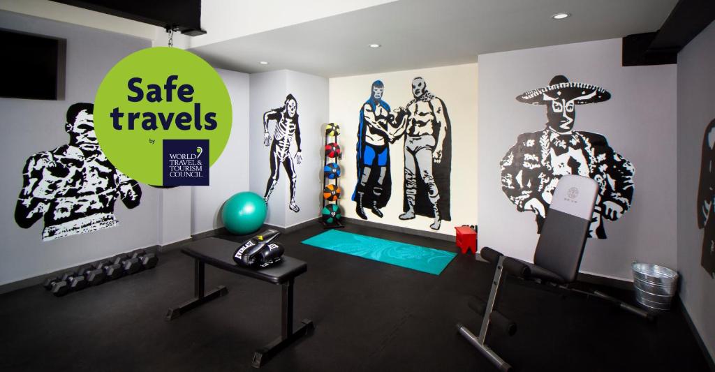 A compact hotel fitness room with weights, a bench, and exercise equipment.