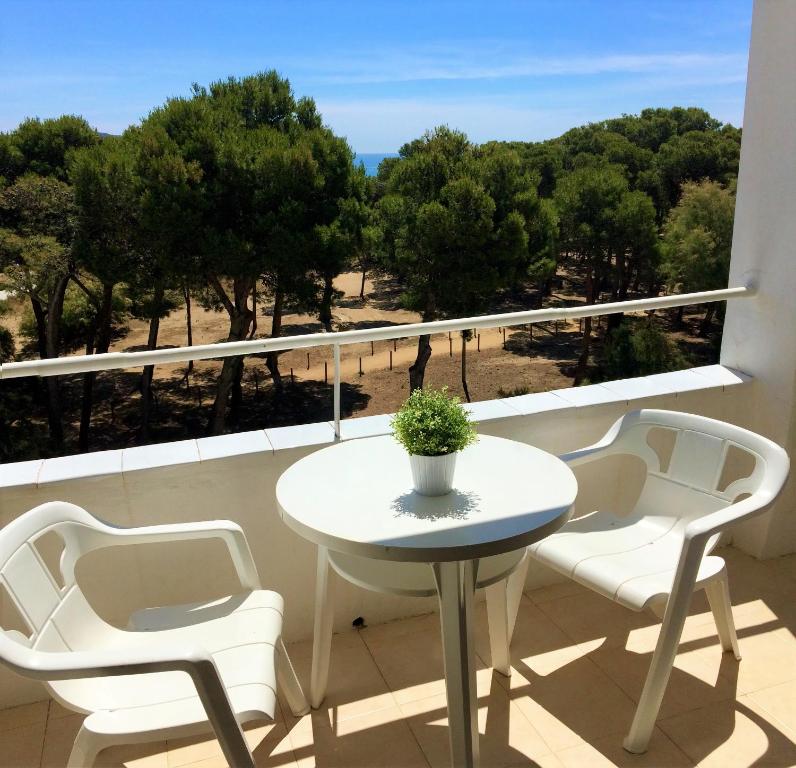 a white table and chairs on a balcony with trees at Trill Mirasol E estudio 1a linea mar in L'Estartit