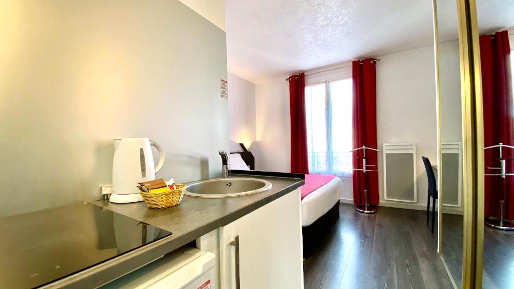 a bathroom with a sink and a bed with red curtains at Boulogne Résidence Hotel in Boulogne-Billancourt