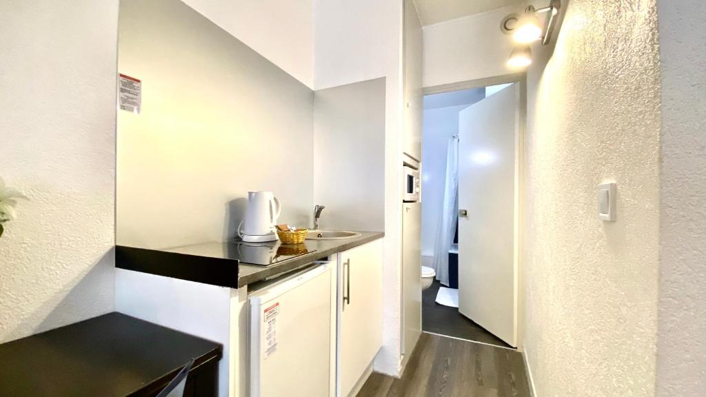 a small kitchen with white cabinets and a hallway at Boulogne Résidence Hotel in Boulogne-Billancourt