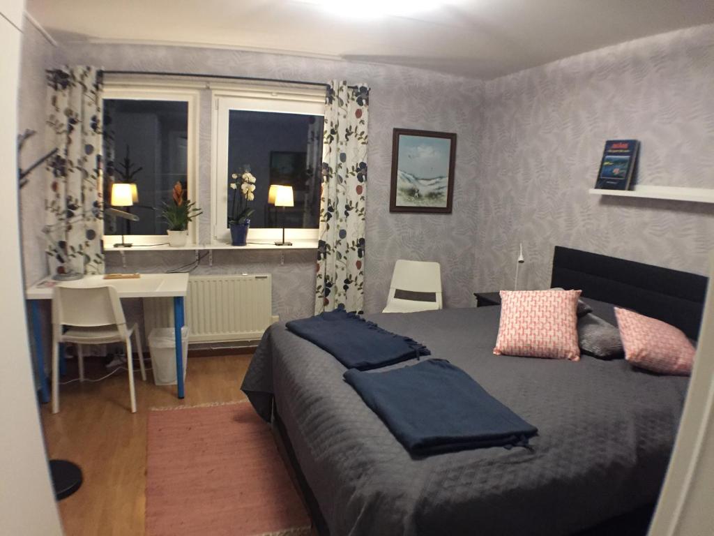 1 dormitorio con cama, mesa y ventana en Dubbelrum med extrasäng på markplan i lugnt villaområde, en Malmö