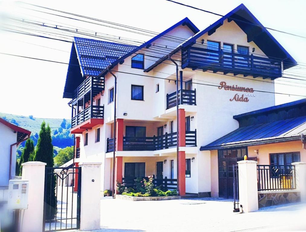 un edificio blanco con balcones azules en una calle en Pensiunea Aida, en Gura Humorului