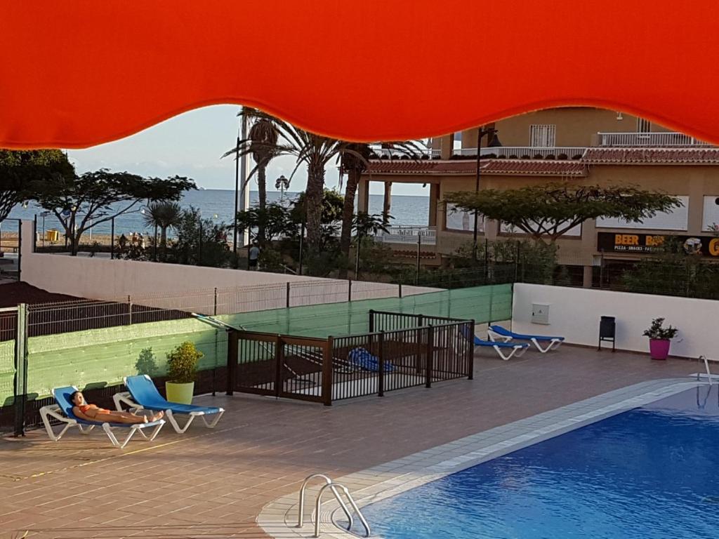 a view of a swimming pool with chairs and a building at PLAYA LAS VISTAS LOFT in Los Cristianos