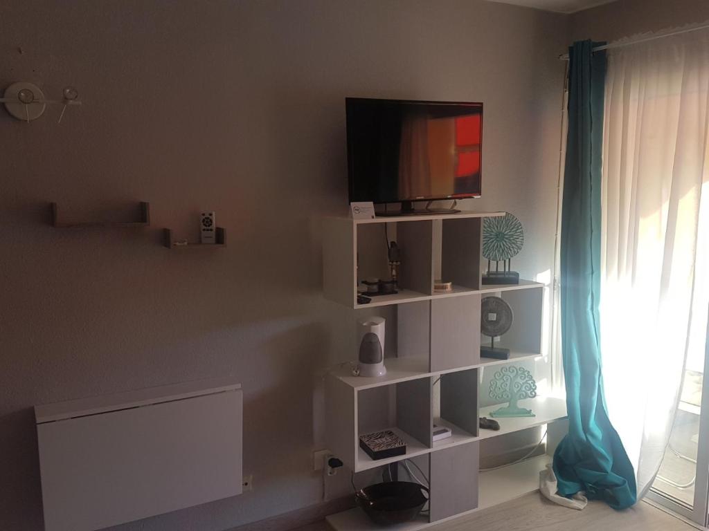 a living room with a tv on a white shelf at PLAYA LAS VISTAS LOFT in Los Cristianos