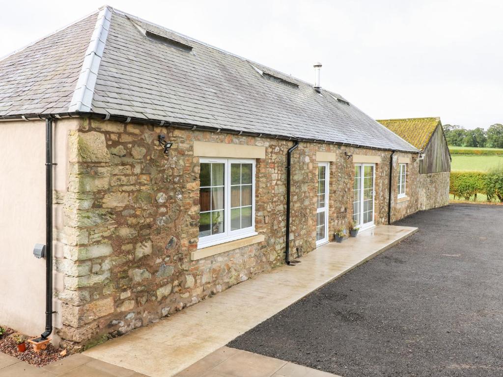 an old stone building with a driveway in front of it at The Old Byre in Jedburgh