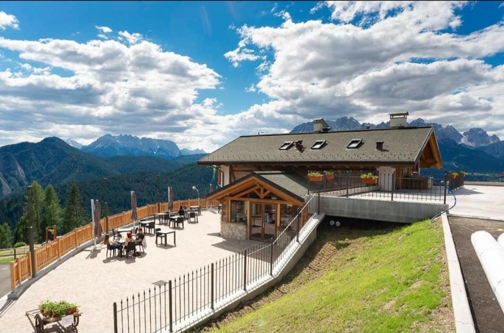 um edifício com mesas e cadeiras e montanhas ao fundo em Locanda La Baita em Santo Stefano di Cadore