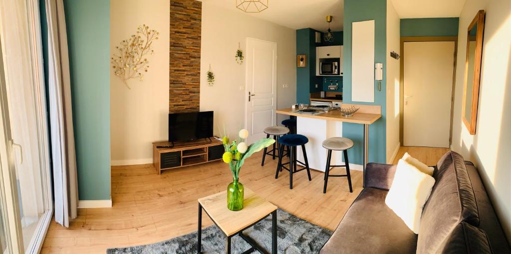 una sala de estar con sofá y un jarrón de flores sobre una mesa en Un confort chaleureux au Rendez-vous en Roques Sur Garonne