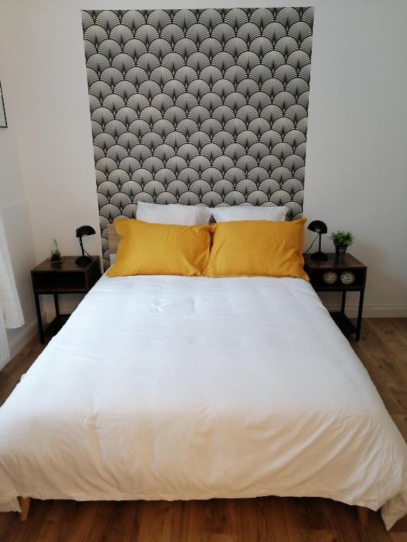 - une chambre avec un grand lit blanc et des oreillers jaunes dans l'établissement Au pied des remparts ..., à Boulogne-sur-Mer